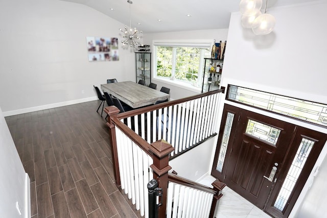 stairway featuring vaulted ceiling, a notable chandelier, wood finished floors, and baseboards