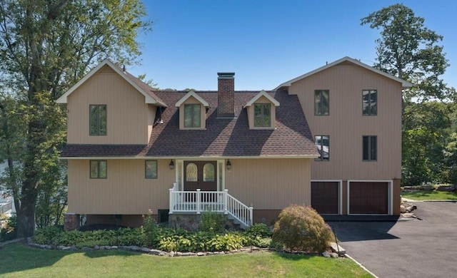 view of front facade with a garage, driveway, a shingled roof, and a chimney