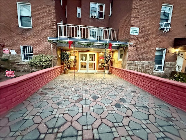 exterior space featuring french doors, brick siding, a patio area, cooling unit, and driveway