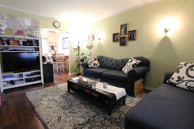 living room featuring arched walkways, ornamental molding, dark wood finished floors, and baseboards