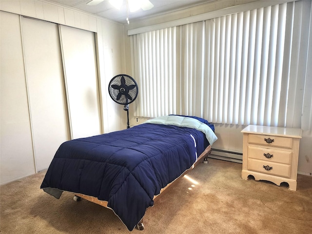 bedroom featuring light carpet, a closet, and a baseboard radiator