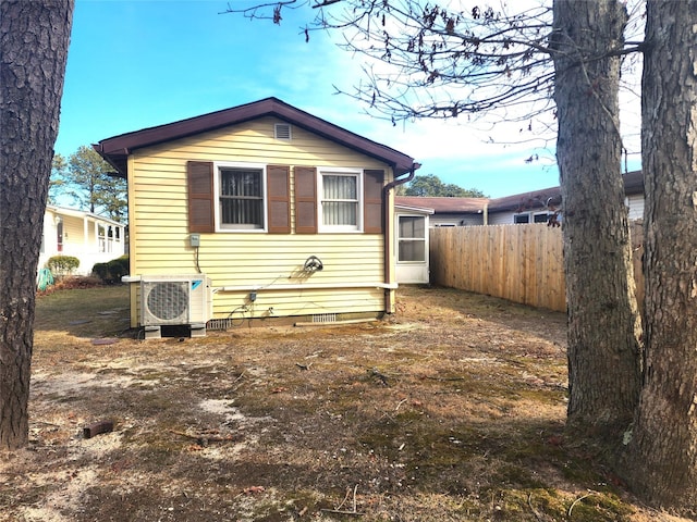 rear view of house with ac unit, crawl space, and fence