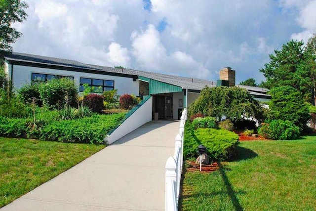 view of front facade with a carport, concrete driveway, and a front lawn