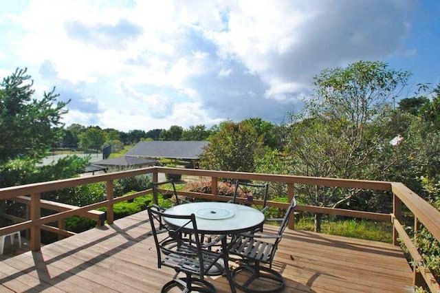 wooden terrace with outdoor dining area and a water view