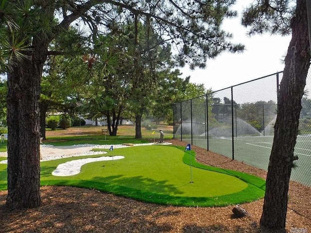 view of home's community featuring view of golf course, a tennis court, and fence