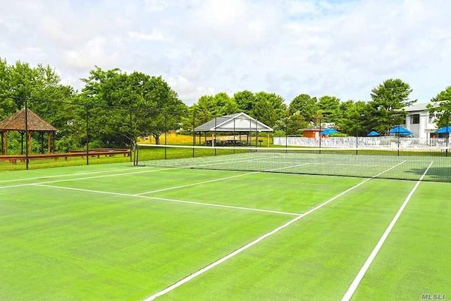 view of tennis court with fence and a gazebo