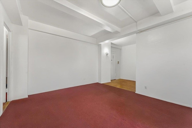 unfurnished room with beamed ceiling and carpet