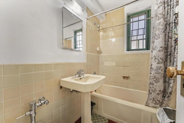 bathroom featuring a wainscoted wall, shower / tub combo with curtain, and tile walls