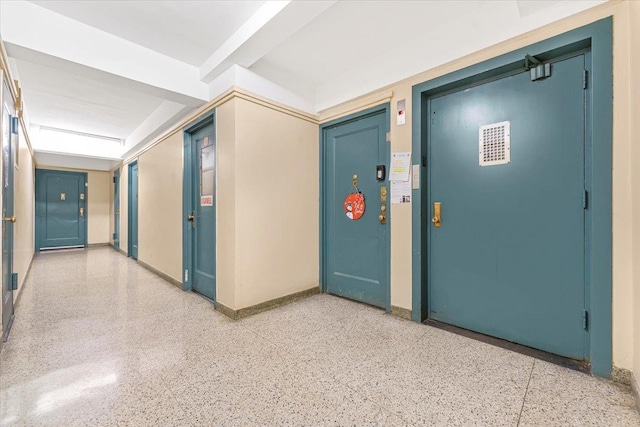 corridor featuring baseboards and light speckled floor