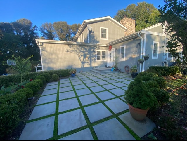 rear view of house with a chimney and a patio