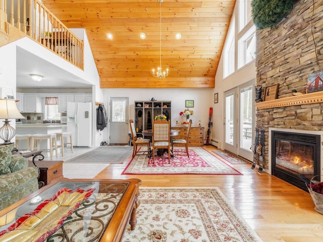 dining space with a towering ceiling, plenty of natural light, light wood-style flooring, and a notable chandelier