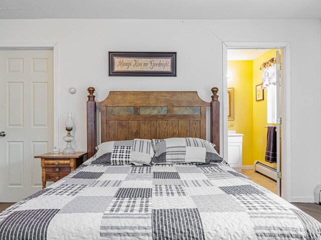 bedroom with carpet, baseboards, baseboard heating, and connected bathroom