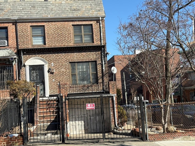 view of front of house featuring brick siding, mansard roof, a fenced front yard, and a gate