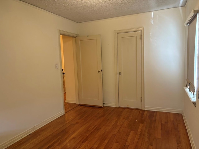 unfurnished bedroom featuring a textured ceiling, baseboards, and wood finished floors