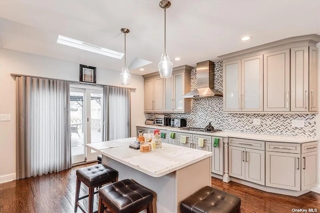 kitchen with lofted ceiling, decorative light fixtures, a center island, light countertops, and wall chimney range hood