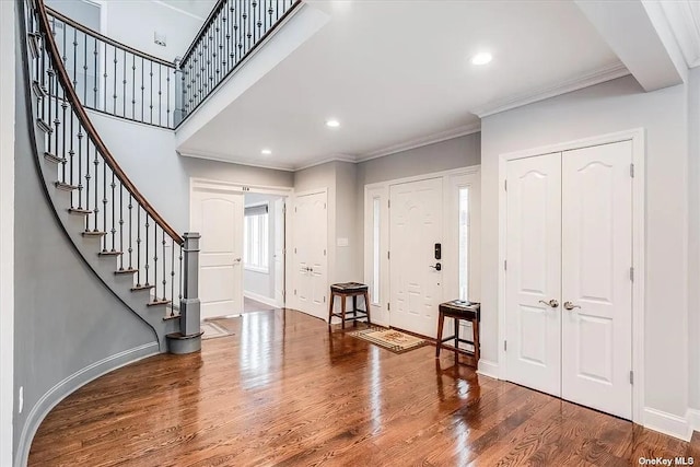 foyer featuring ornamental molding, stairs, baseboards, and wood finished floors