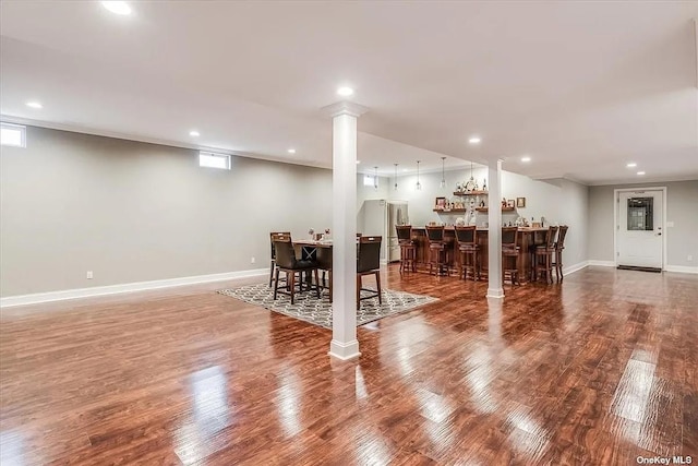 interior space with freestanding refrigerator, indoor bar, baseboards, and wood finished floors