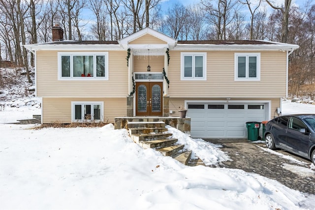 bi-level home with french doors, a chimney, and an attached garage