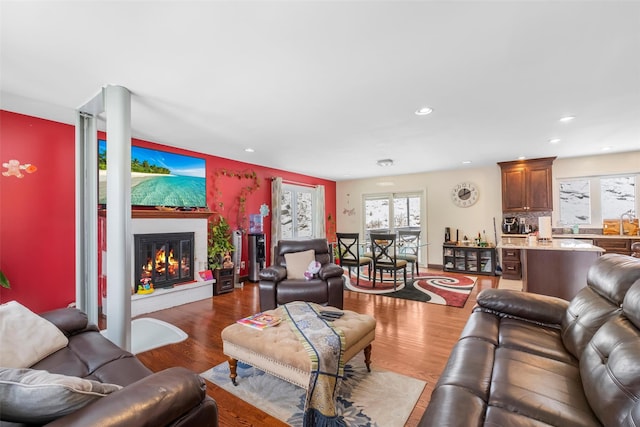 living room with a glass covered fireplace, wood finished floors, and recessed lighting