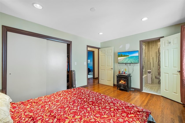 bedroom with light wood-type flooring, ensuite bathroom, a closet, and recessed lighting