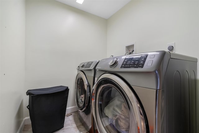 washroom featuring laundry area, baseboards, and washing machine and clothes dryer