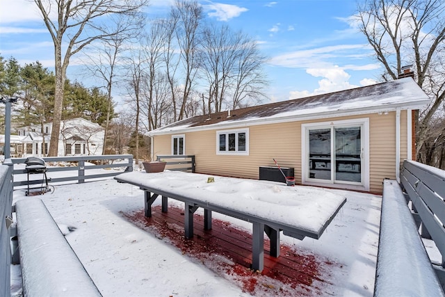 snow covered rear of property with a chimney and fence