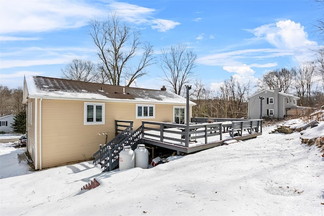 snow covered back of property with a deck