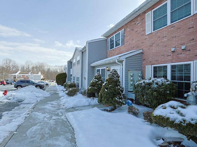 snow covered property featuring brick siding