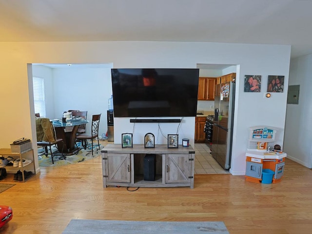 living room with light wood finished floors, electric panel, and baseboards