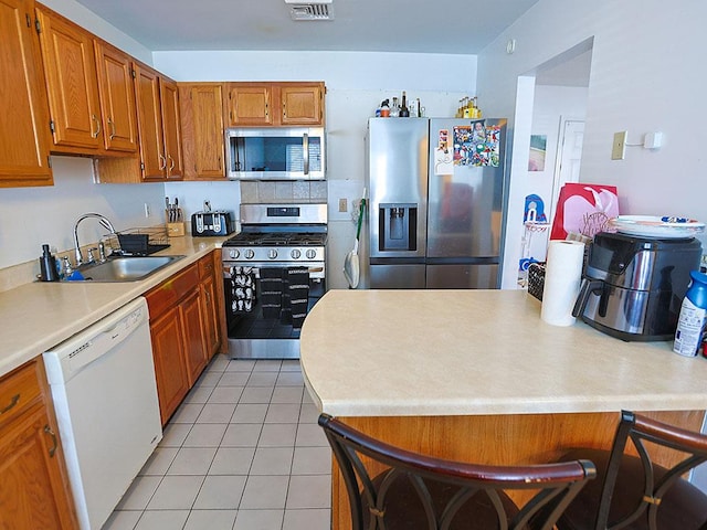 kitchen with stainless steel appliances, light countertops, visible vents, and brown cabinets