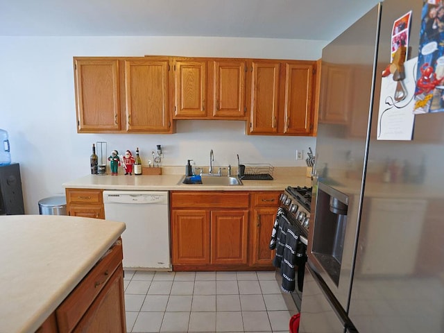 kitchen with appliances with stainless steel finishes, brown cabinets, light countertops, and a sink