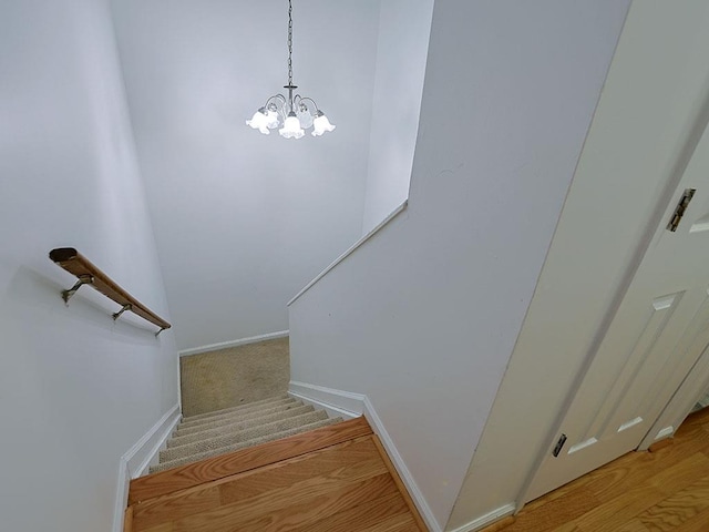 stairs featuring an inviting chandelier and baseboards