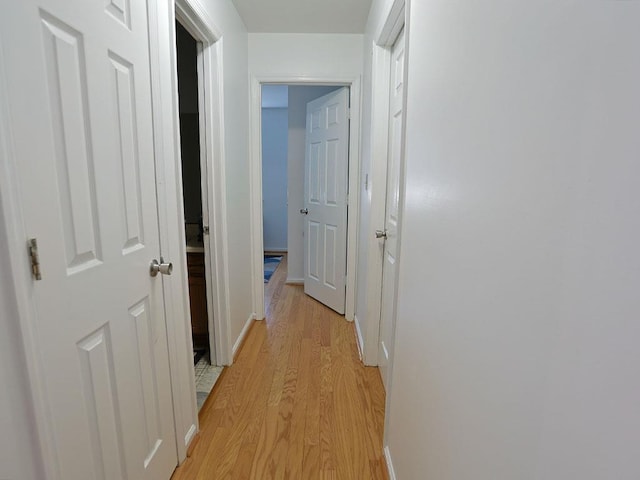 corridor featuring baseboards and light wood-style floors