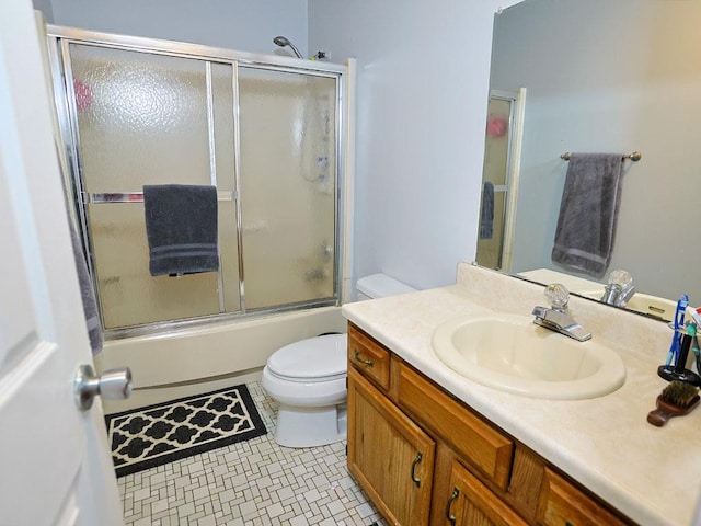 bathroom with toilet, shower / bath combination with glass door, vanity, and tile patterned floors