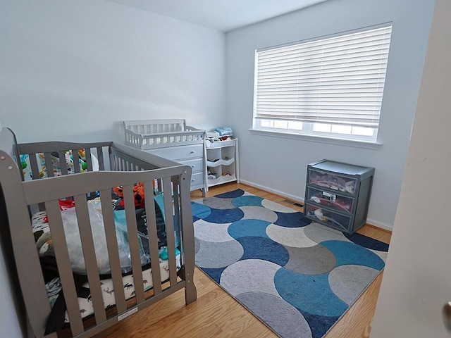 bedroom with visible vents, baseboards, and wood finished floors