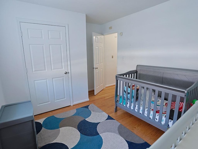 bedroom with a crib, baseboards, and wood finished floors