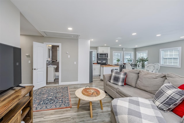 living area featuring attic access, recessed lighting, light wood-style flooring, and baseboards