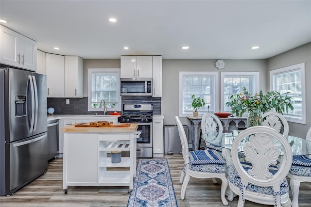 kitchen featuring light wood finished floors, appliances with stainless steel finishes, white cabinets, and a sink