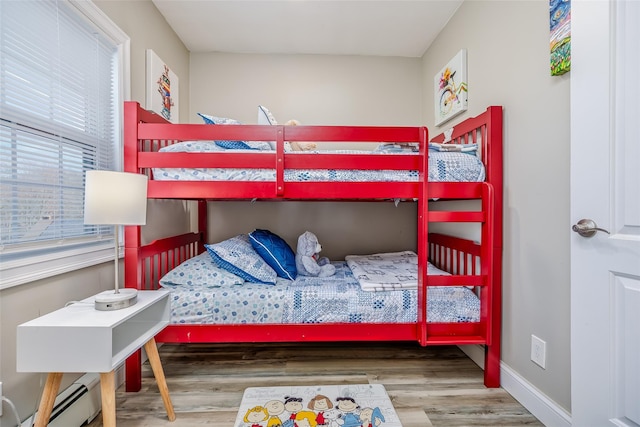 bedroom featuring a baseboard radiator, wood finished floors, and baseboards