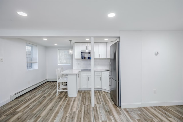 kitchen with a baseboard radiator, decorative light fixtures, light countertops, stainless steel appliances, and white cabinetry