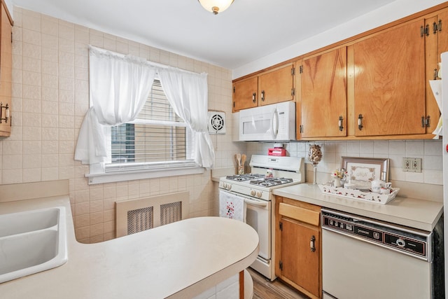 kitchen featuring white appliances, visible vents, brown cabinetry, light countertops, and tile walls