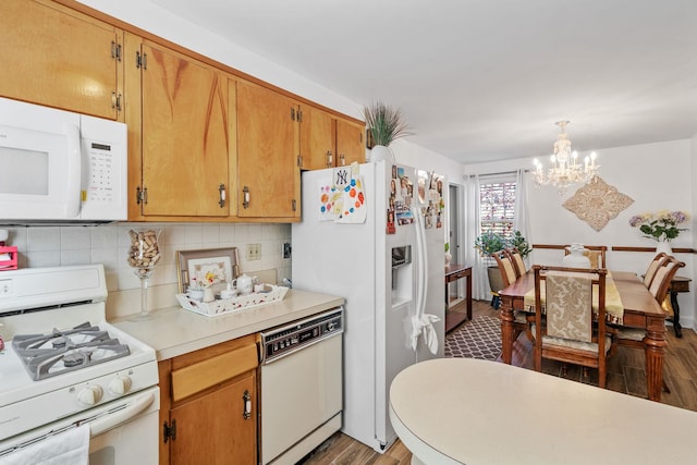 kitchen with brown cabinets, light countertops, hanging light fixtures, wood finished floors, and white appliances