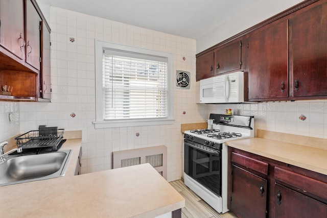 kitchen featuring white appliances, light countertops, a sink, and tile walls