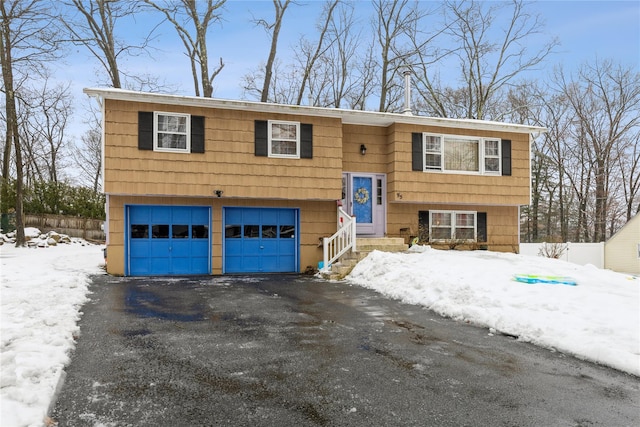 raised ranch with an attached garage, aphalt driveway, and entry steps