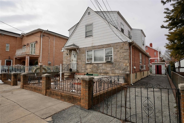 view of front of property with a fenced front yard, cooling unit, stone siding, and a gate