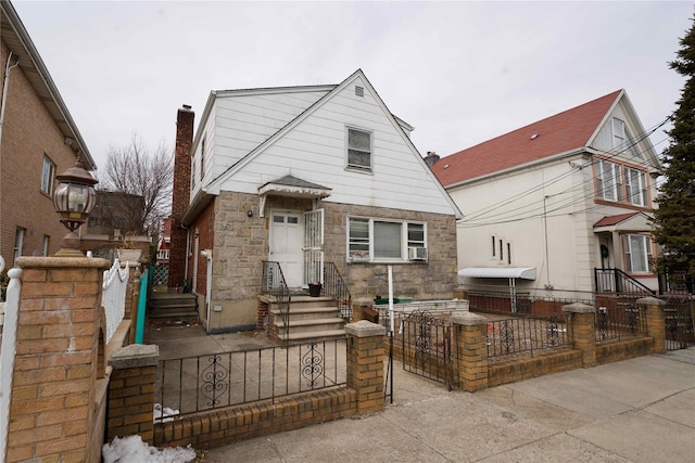 view of front facade with a fenced front yard, a chimney, cooling unit, and a gate