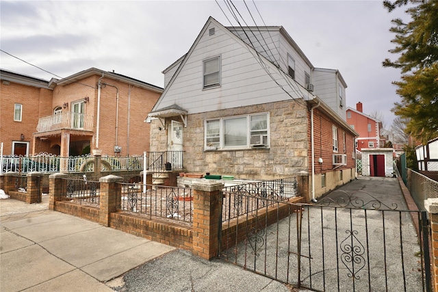 view of front of house featuring stone siding, a fenced front yard, cooling unit, and a gate