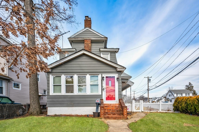 view of front facade featuring a front yard, fence, a chimney, and entry steps