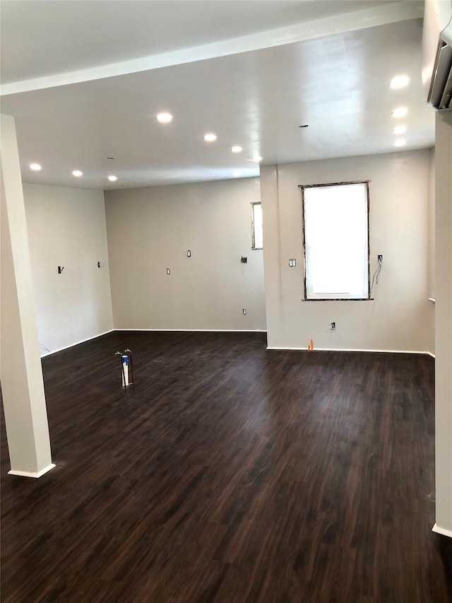 empty room with dark wood-style floors, recessed lighting, and an AC wall unit