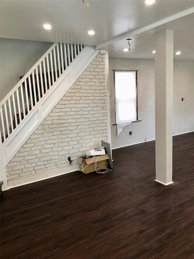 interior space featuring dark wood finished floors, brick wall, and stairs